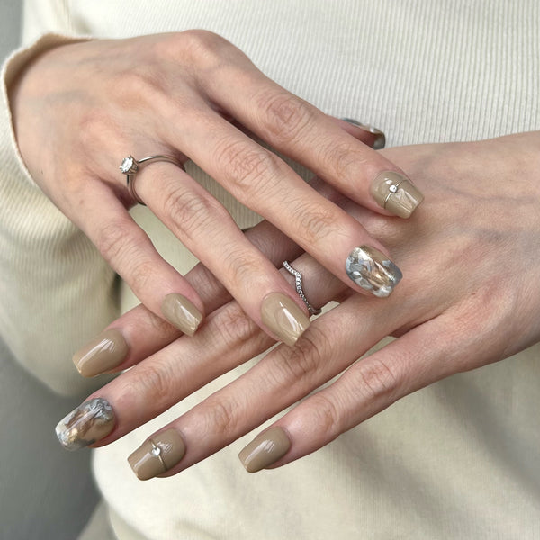 女生貼上大地色的暈染假甲片 A girl is wearing earthy tone marble false nails