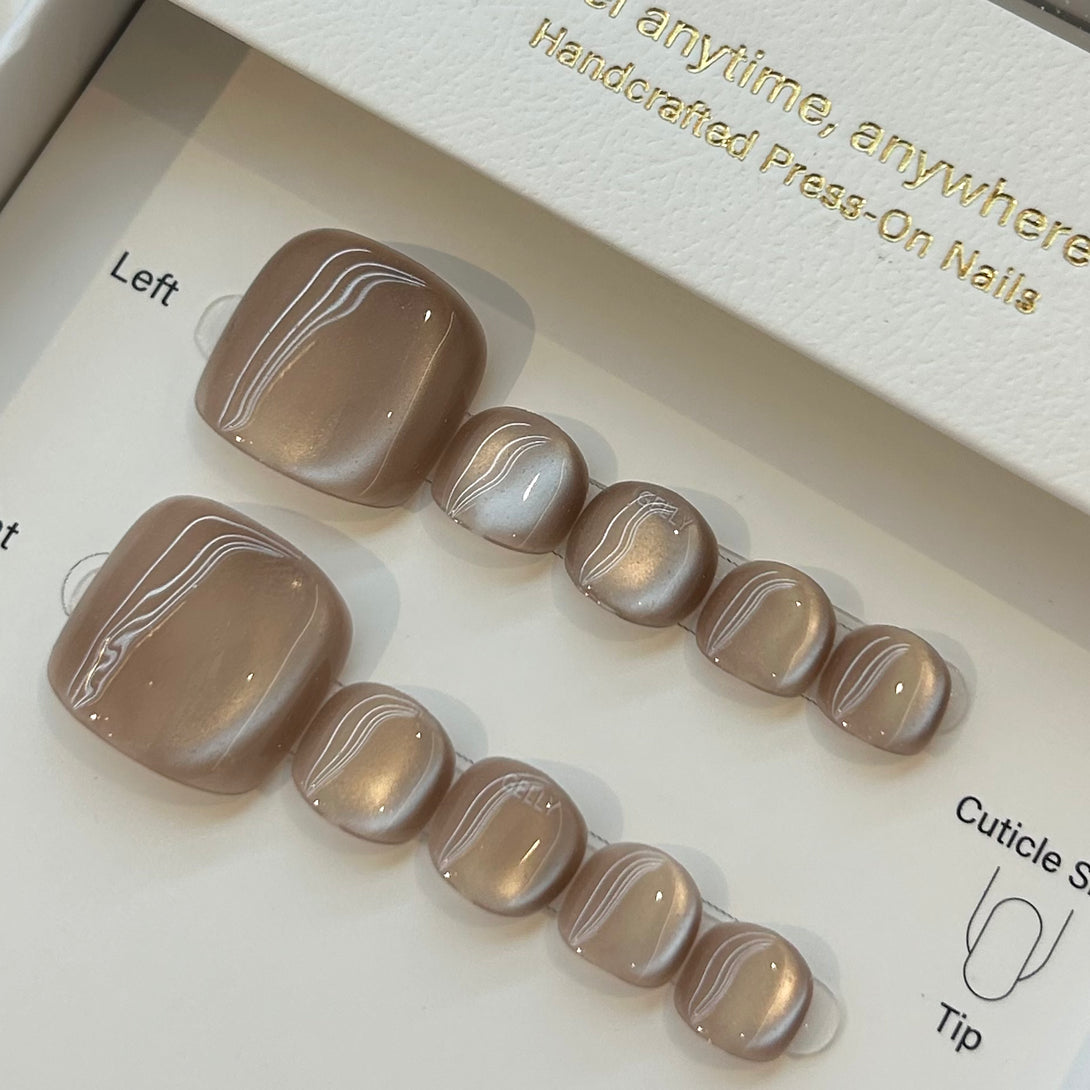 Set of press-on nails with a neutral color scheme on a branded box.