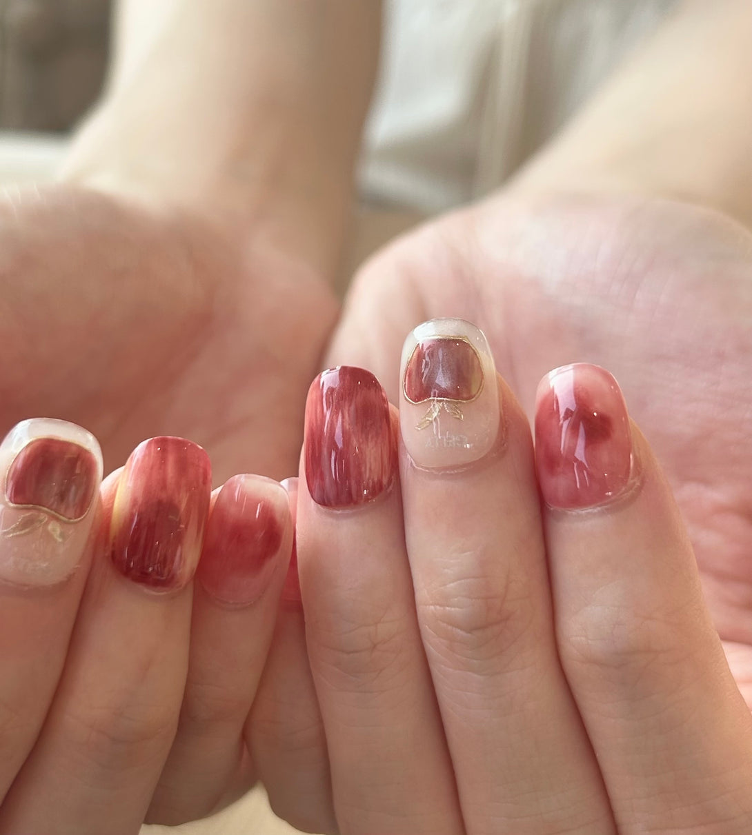Close-up of a hand with red and white marbled nail polish.
