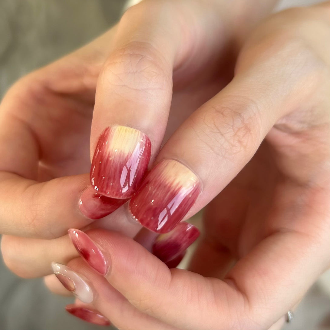Close-up of a hand with red and white gradient nail polish.