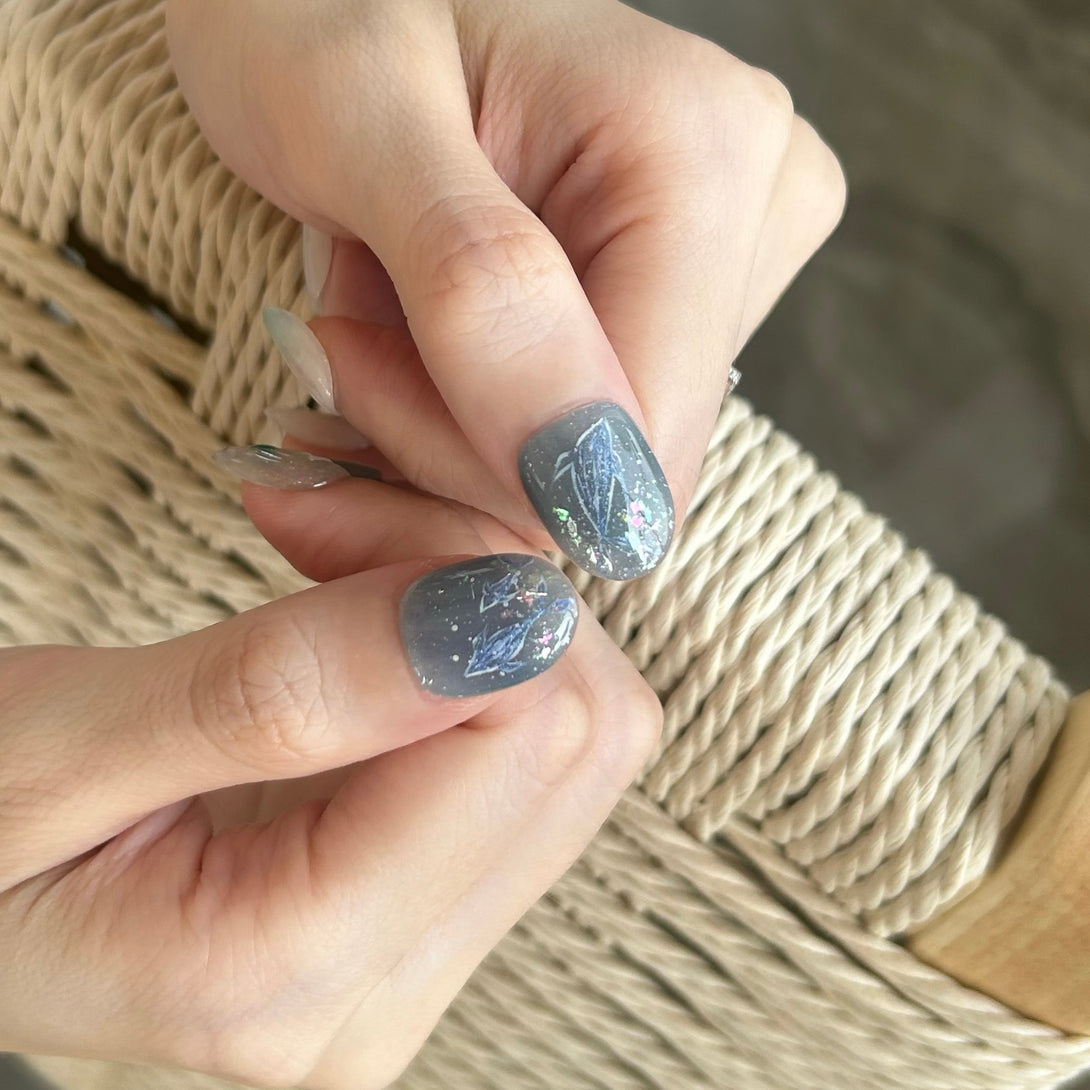 Close-up of hands with gray nail polish on a woven surface