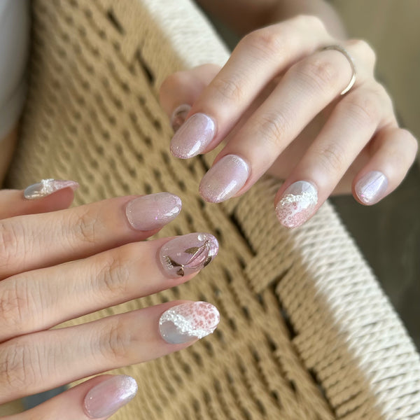 Close-up of hands with pink glittery nail polish on a woven surface.
