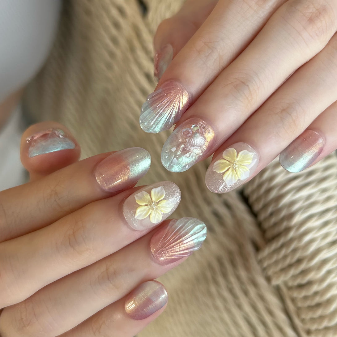 Close-up of hands with decorative nail art featuring flowers and shell designs.